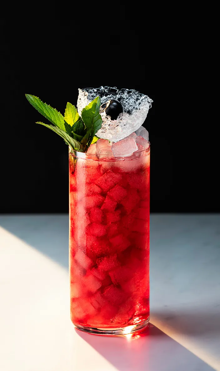 Red watermelon cocktail over crushed ice garnished with fresh mint and a cherry