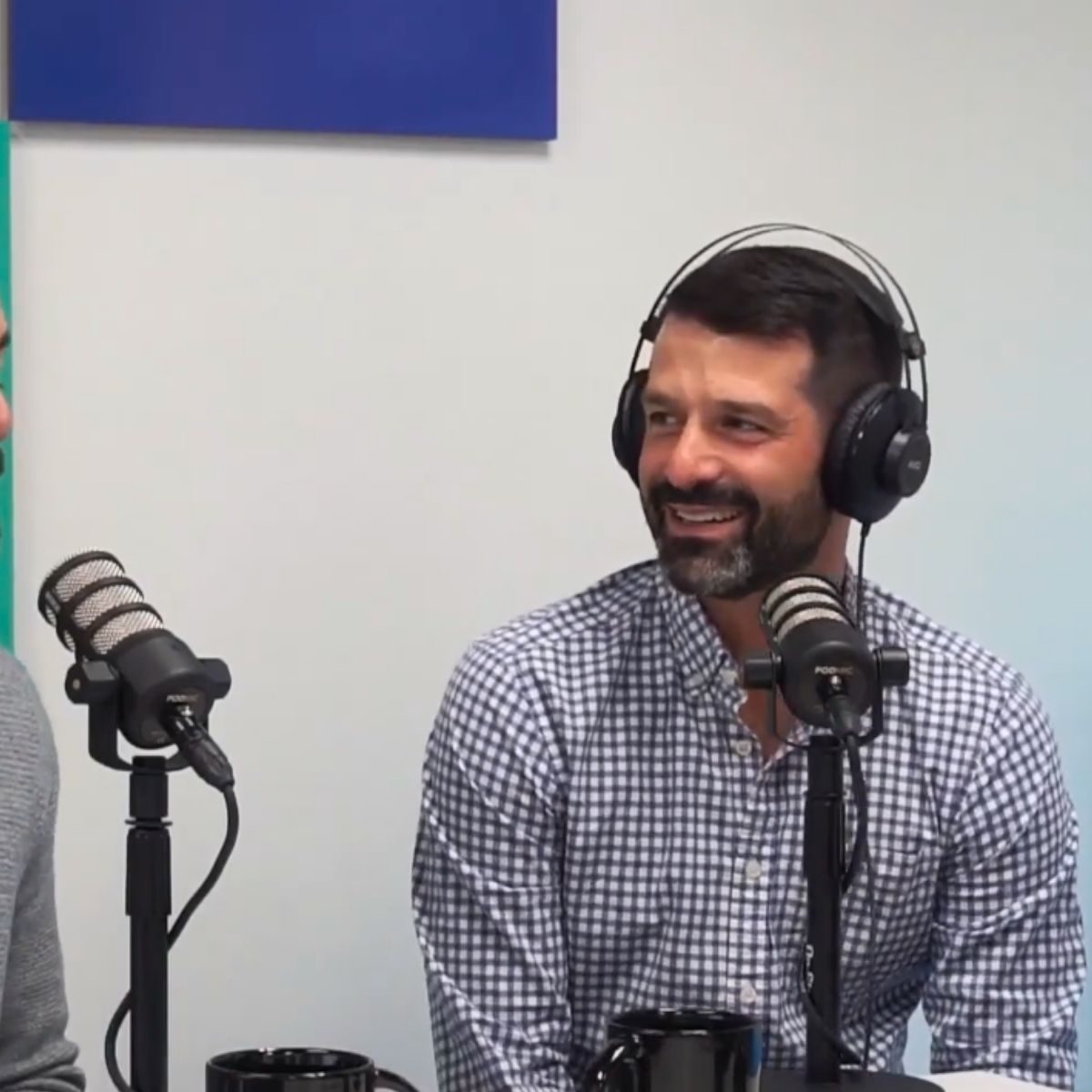ZG Group: Zack delivering industry insight during a podcast. Man wearing headphones and a checkered shirt speaking into a microphone during a podcast or interview.