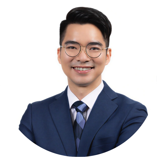 Smiling young man wearing round glasses, a blue suit, white shirt, and patterned tie against a white background.