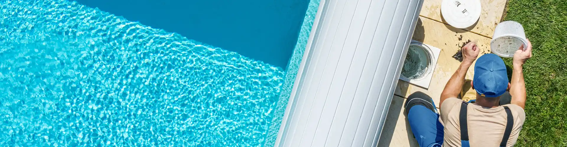 Man in red shirt and cap cleaning the edge of a pool outdoors.