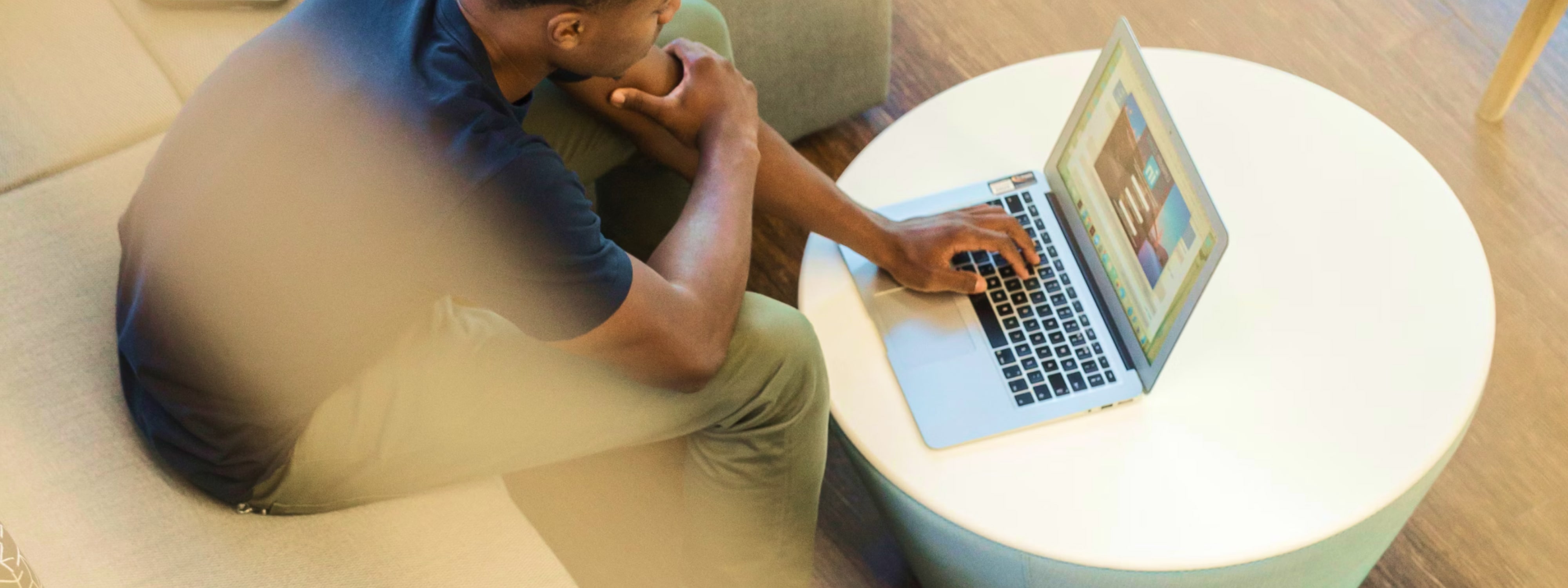 Person sitting at white table working on laptop with thoughtful pose