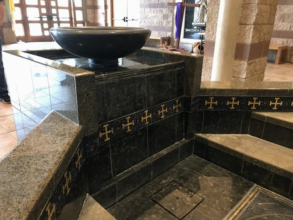 Black vessel sink on marble counter with decorative cross tile border