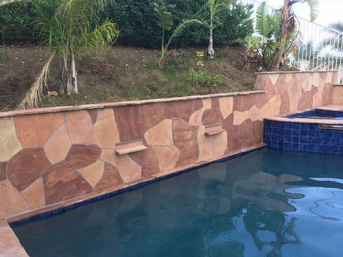 Stone-tiled pool with blue water and tropical garden background