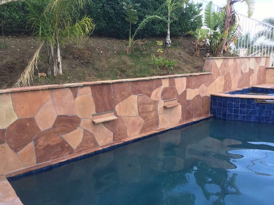 Stone-tiled pool with blue water and tropical garden background