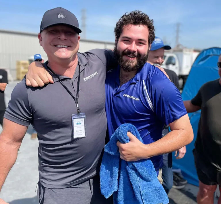 Two smiling coworkers in company shirts posing together outdoors