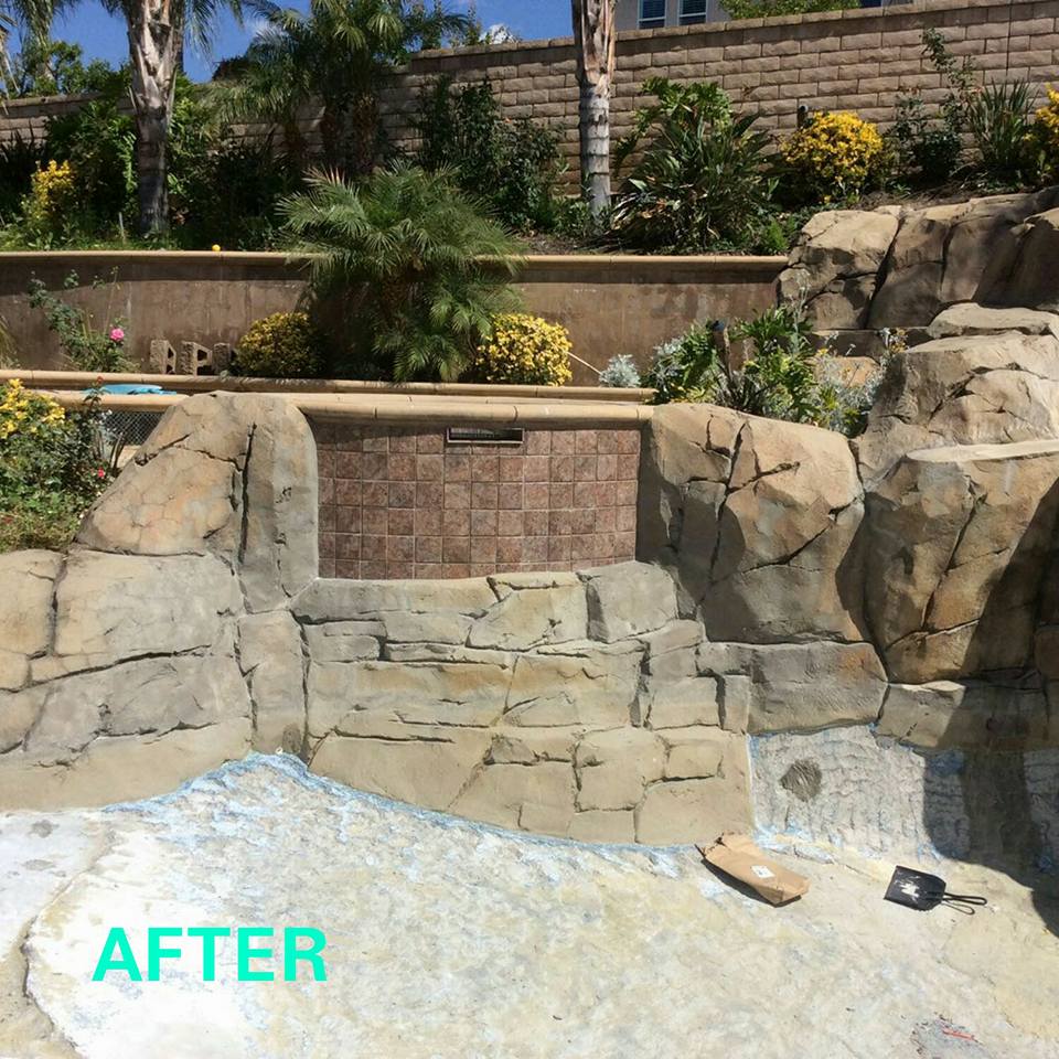 Landscaped rock waterfall with stone walls and yellow flowering plants