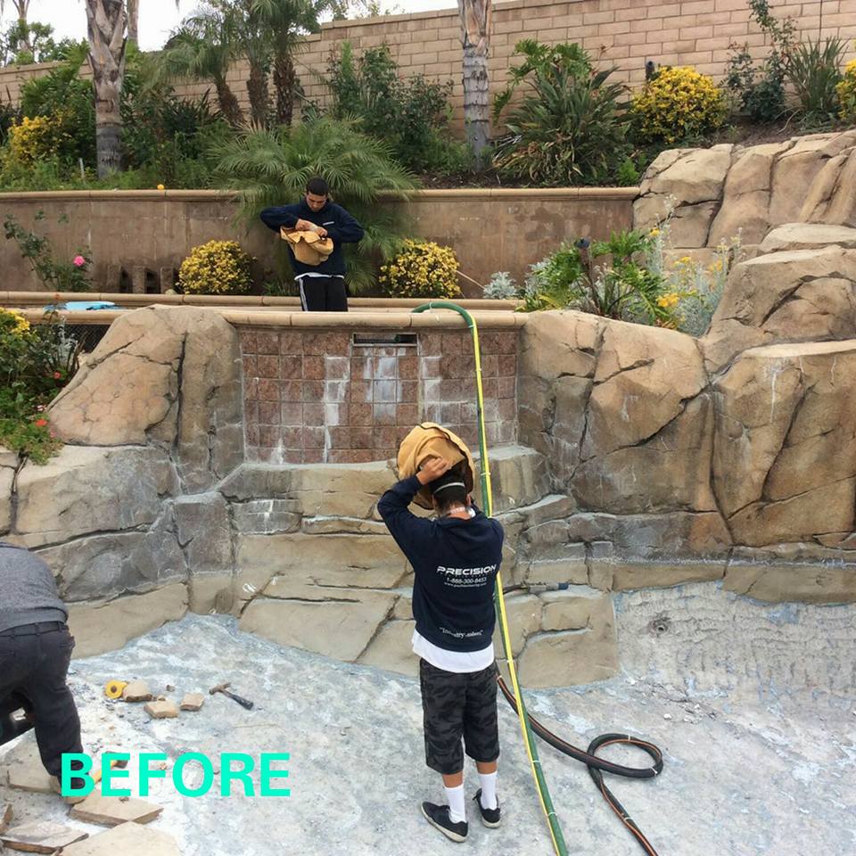 Workers installing rockwork and landscaping in an outdoor garden area