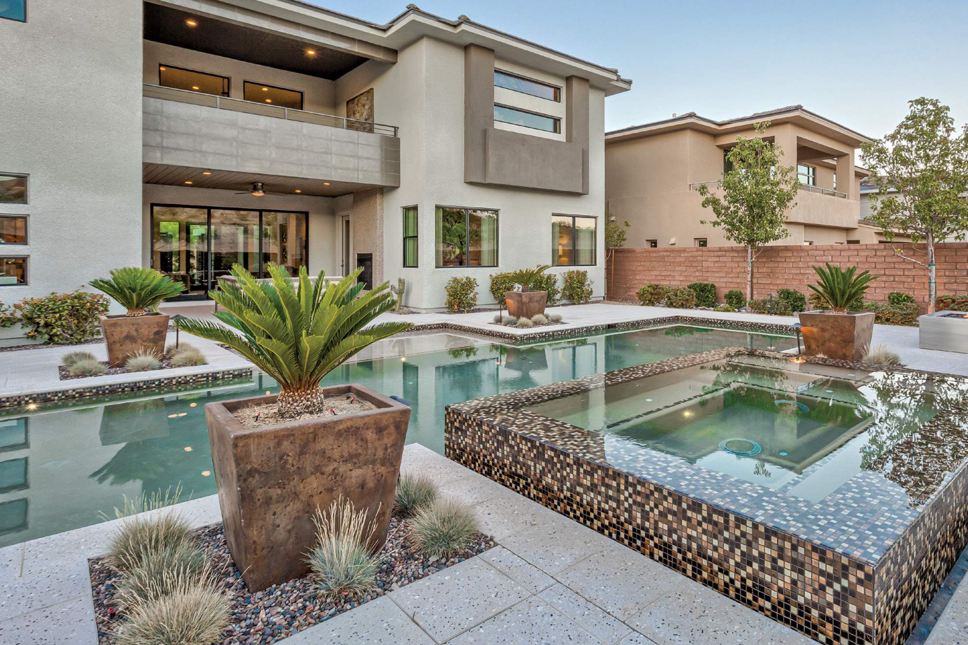 Modern home with multi-level pool, palm plants, and mosaic tile features