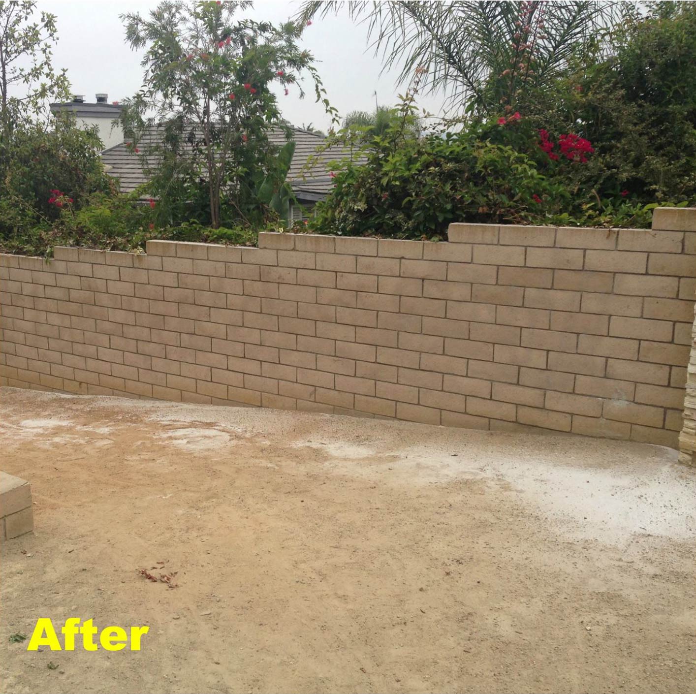 Completed landscaping project with new retaining wall and sandy ground