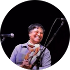 Man and woman smiling and posing together outdoors with greenery in the background.