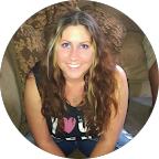 Headshot of a smiling woman with short brown hair, wearing glasses and dangly earrings.