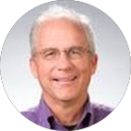 Man and woman sitting on a bench outside with two golden retriever dogs.