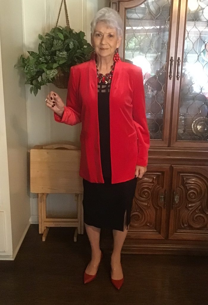 Susan Weaverling wearing a red top reclining on a gray upholstered chair.