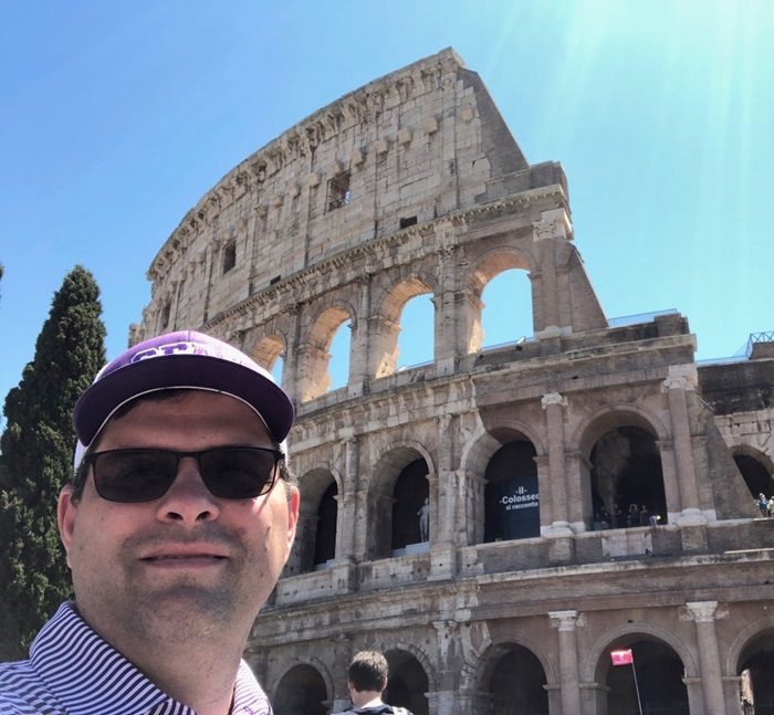 Jerry Keaney wearing glasses and a blue bike helmet standing next to a bicycle on a foggy street near a Fort Crockett Seawall sign.