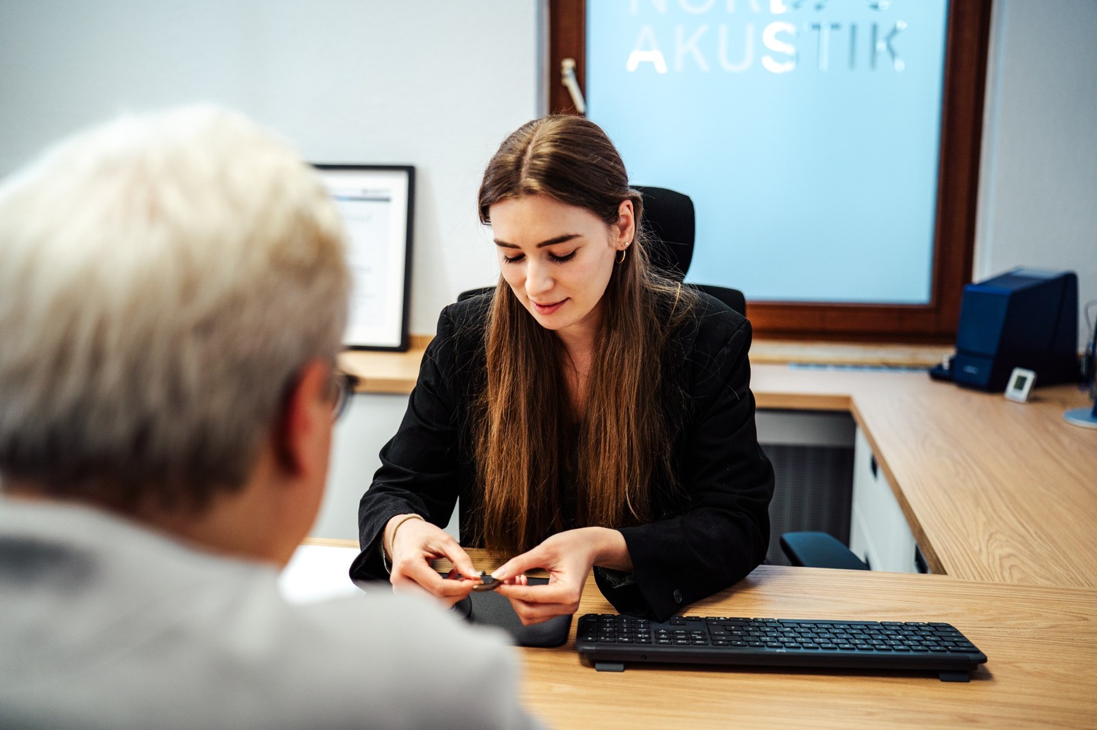 Stadtansicht von Oldenburg mit einer großen Illustration eines braunen Hörgeräts und dem Schriftzug Nord Akustik.