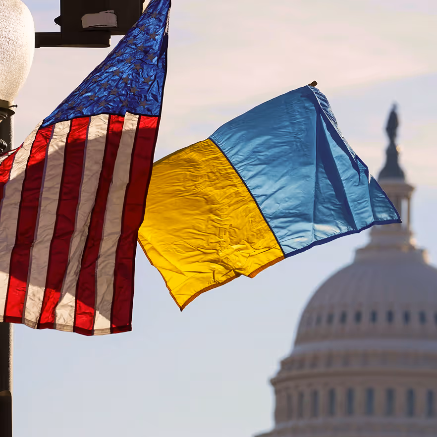 United States and Ukraine flags waving with the U.S. Capitol dome in the background.