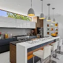 Modern kitchen with white and gray island, three bar stools, hanging pendant lights, and black and white cabinetry.