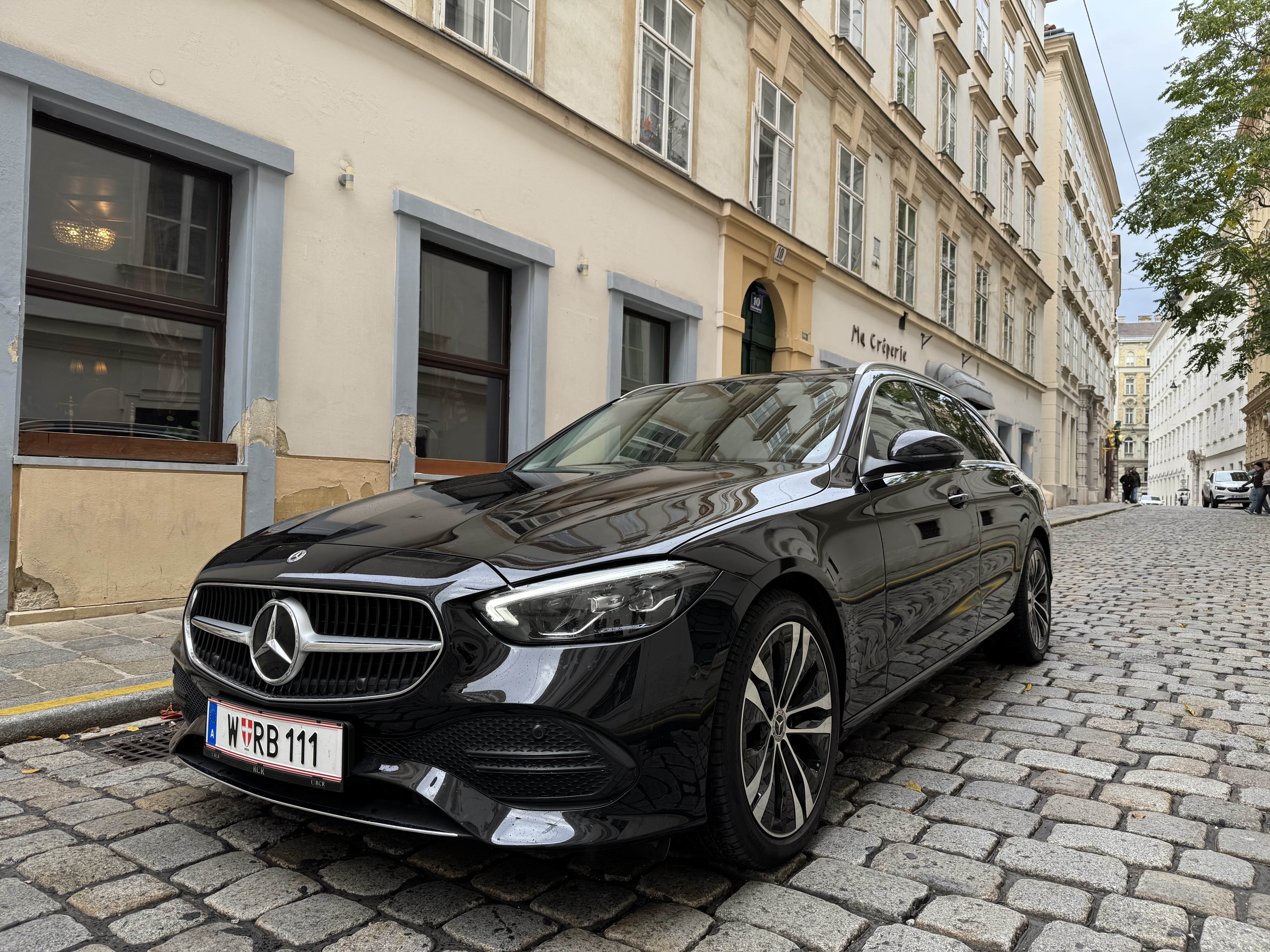Black Mercedes-Benz sedan parked on a cobblestone street with historic buildings in the background.
