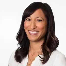 Smiling woman with long dark hair wearing a white blouse against a white background.