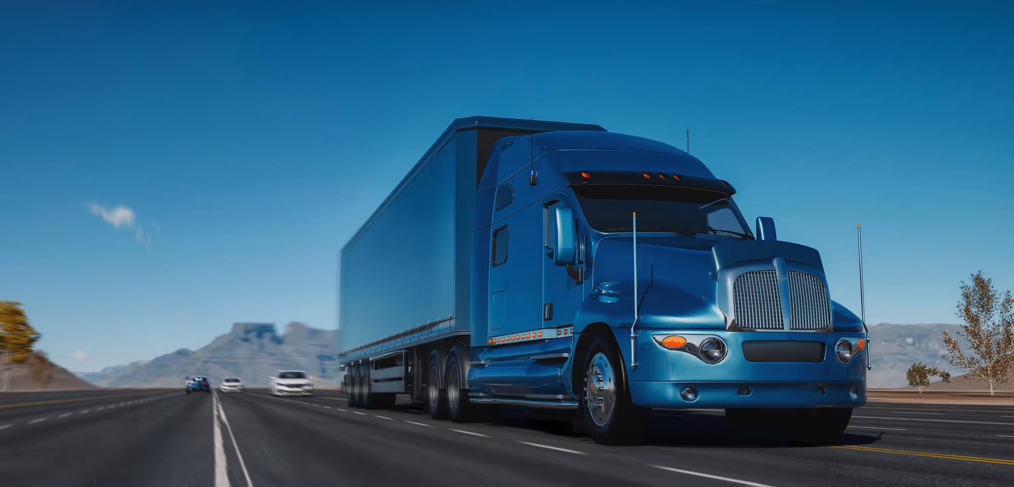 Blue semi-truck driving on highway with mountains in the background under clear blue sky.