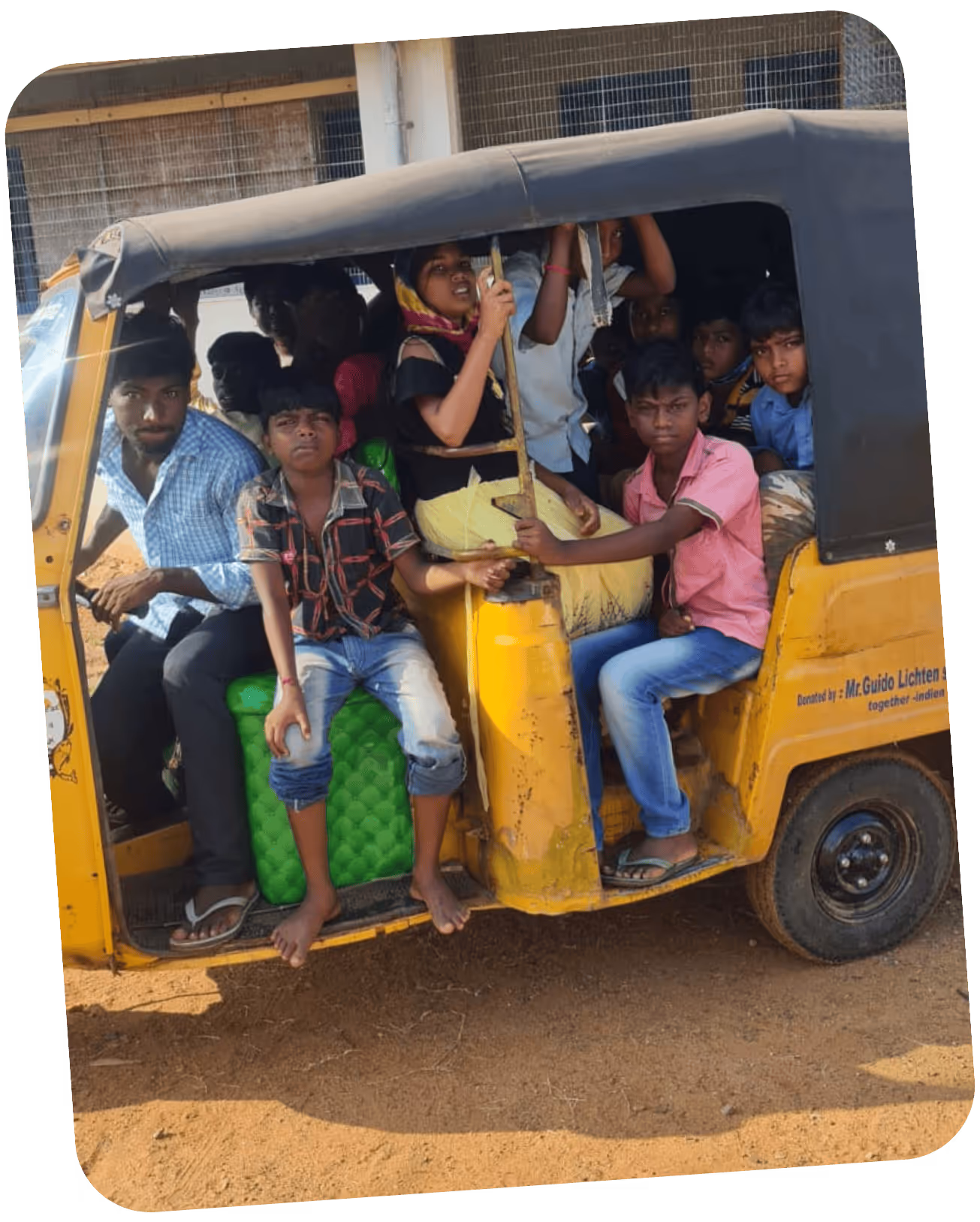 Überfülltes gelbes Motorrad-Taxi mit mehreren Kindern und einem Fahrer auf staubigem Boden.