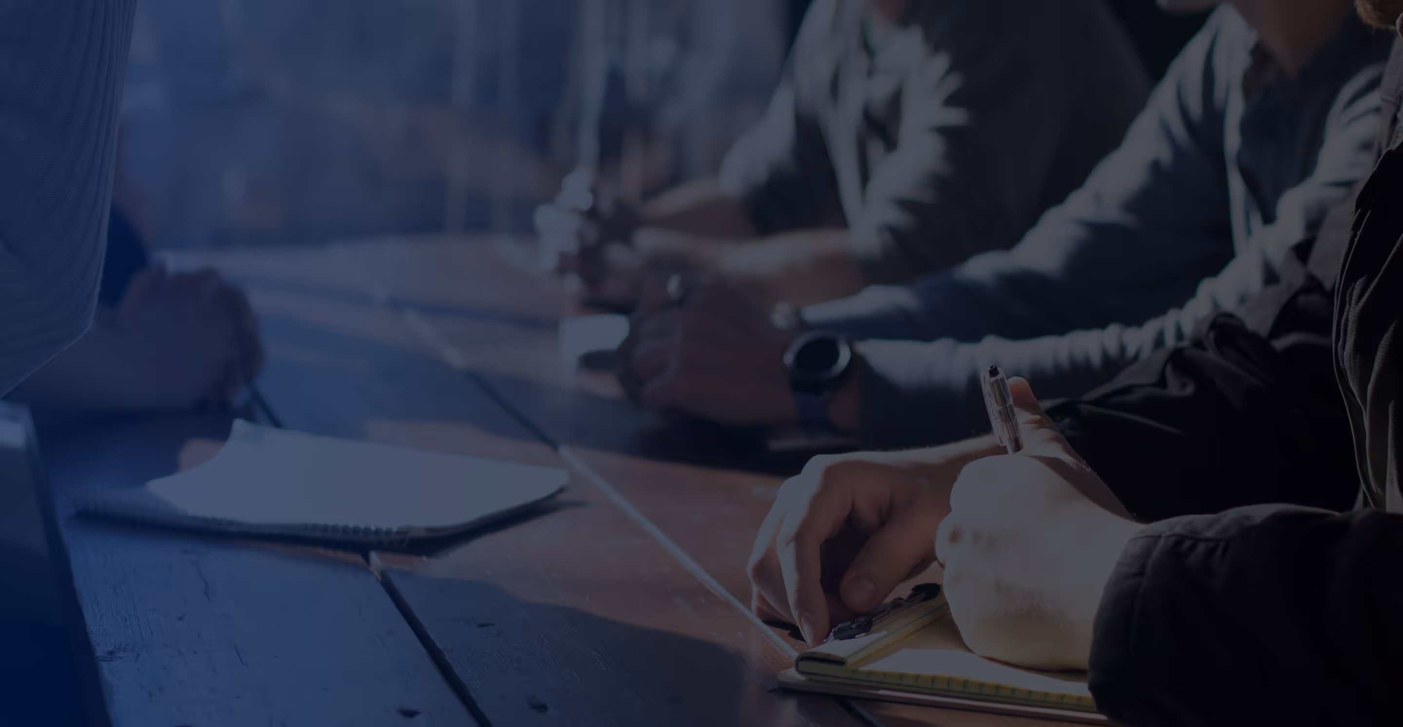 Man in glasses presenting data on a flip chart to seated colleagues in a conference room with bar charts displayed on a screen.