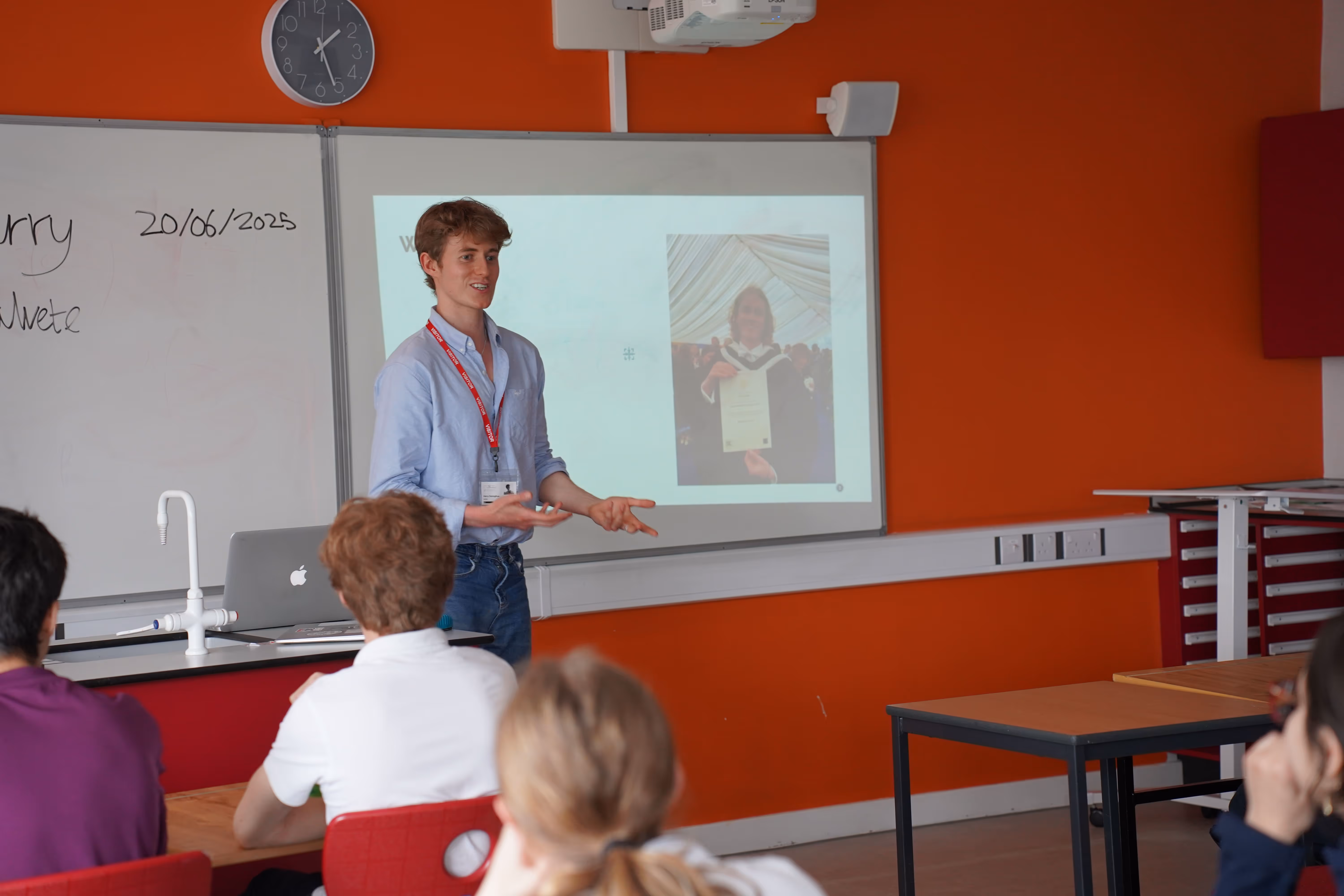 Harry is teaching in front of a classroom and giving a speech.