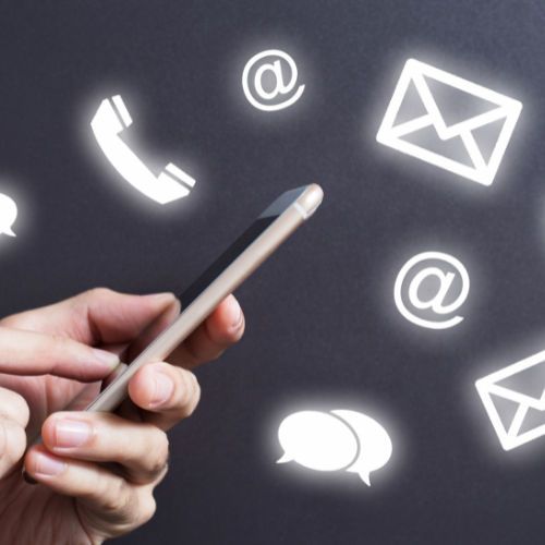 Hand holding a smartphone surrounded by glowing communication icons including phone, email, at symbols, and chat bubbles.