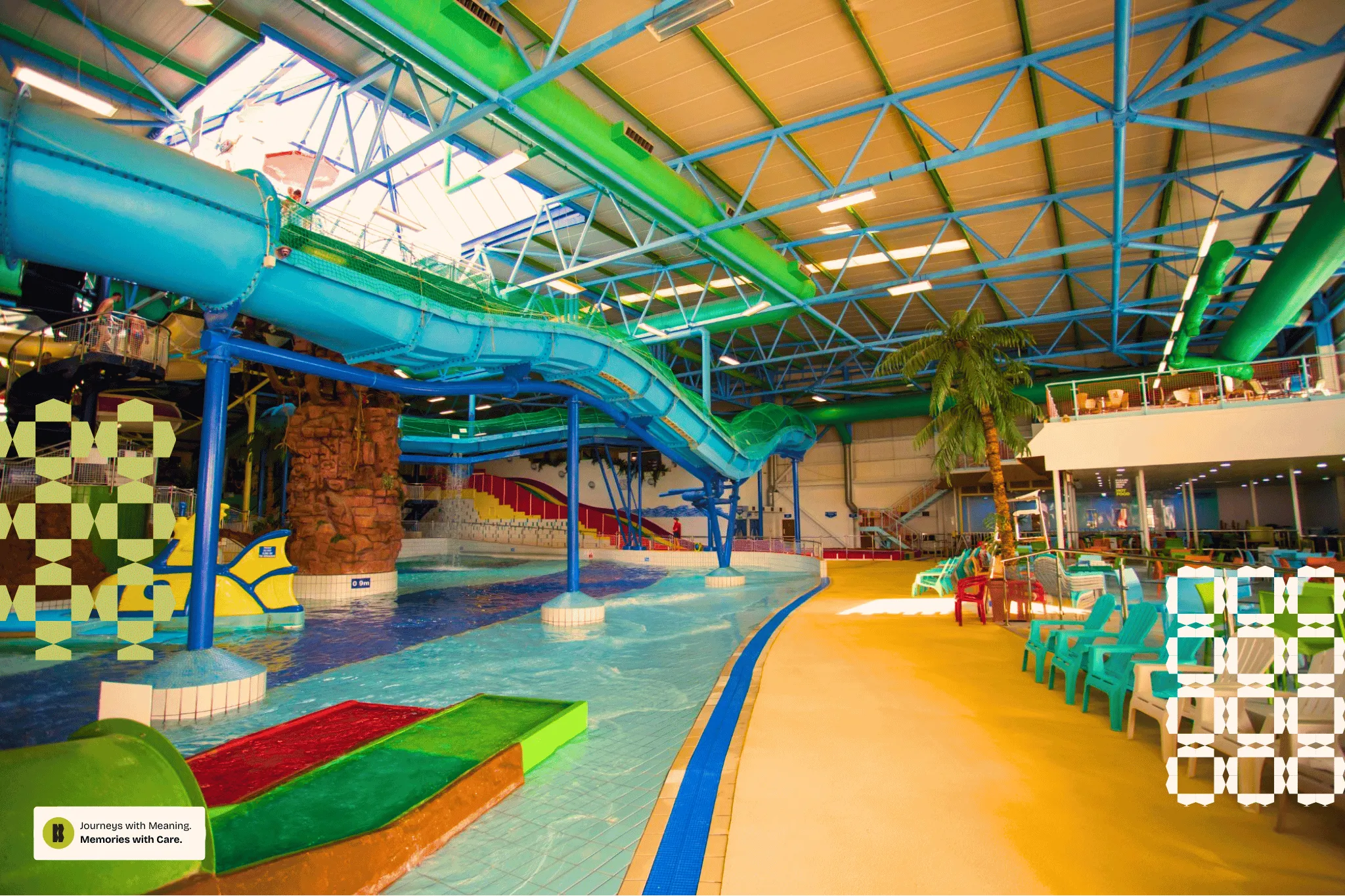 Indoor water park featuring a large blue water slide, a lazy river, colorful play structures, and poolside chairs with a faux palm tree.