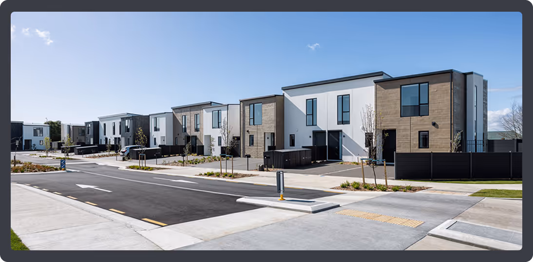Modern townhouse complex with two-story units featuring mixed wood and white panel exteriors, black fences, and landscaped surroundings.