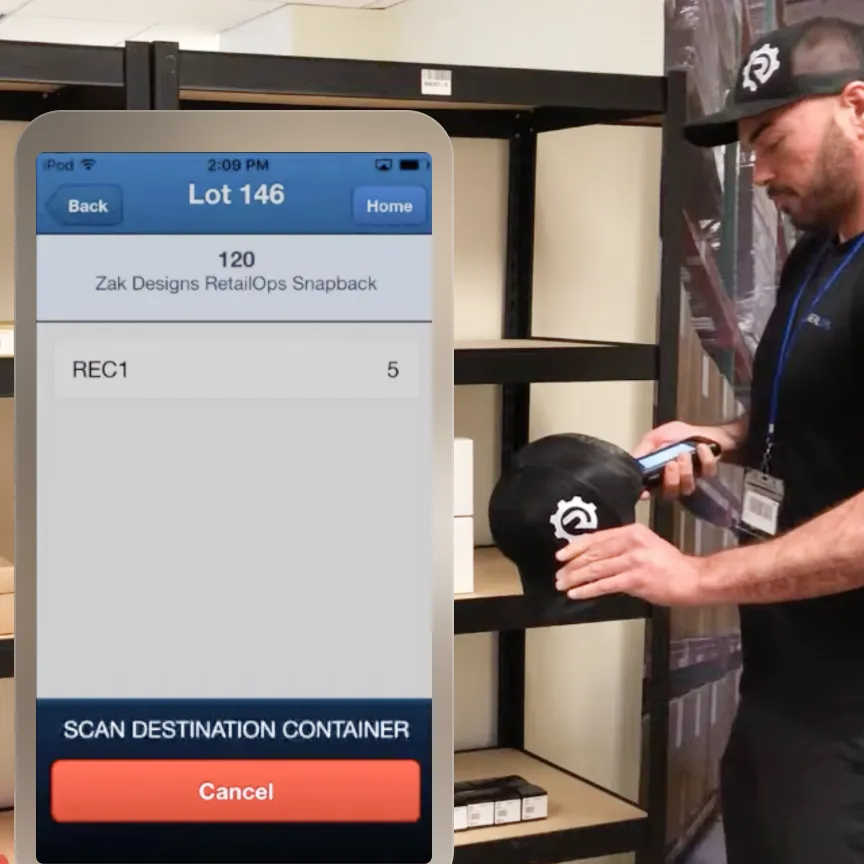 Man scanning a black snapback hat with a barcode scanner near empty shelves, with a mobile screen in foreground showing inventory details for Lot 146 of Zak Designs RetailOps Snapback, quantity 5, and a prompt to scan destination container.
