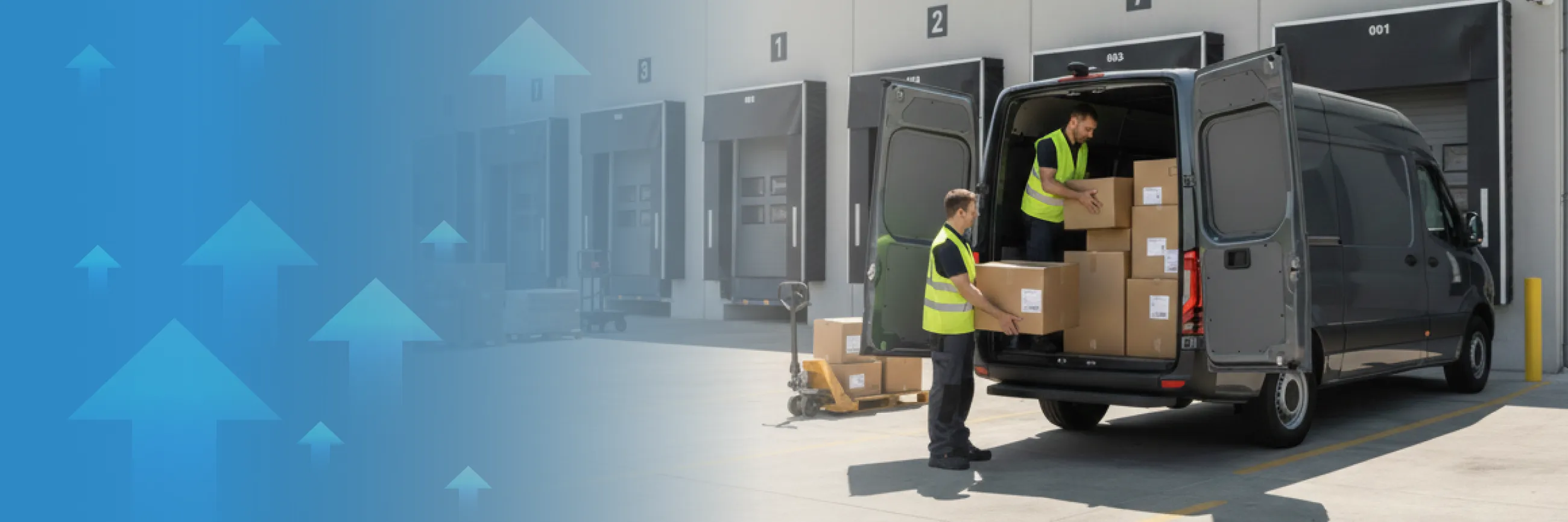 Two workers in yellow safety vests unloading boxes from the back of a black delivery van at a warehouse loading dock.