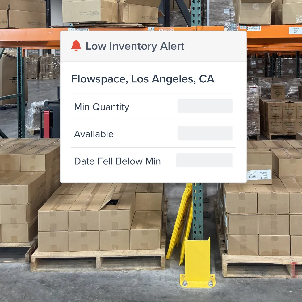Warehouse with stacked cardboard boxes on wooden pallets and an overlay showing a low inventory alert for Flowspace, Los Angeles, CA.