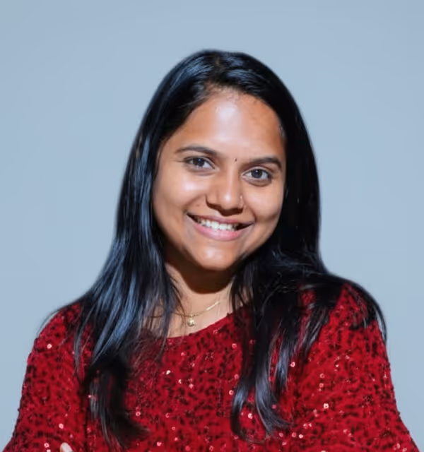 Smiling woman with long black hair wearing a red sequined top against a plain background.