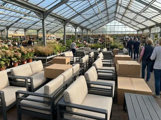 Allée de jardinerie encombrée de salons de jardin identiques invendus et de cartons empilés en fin de saison
