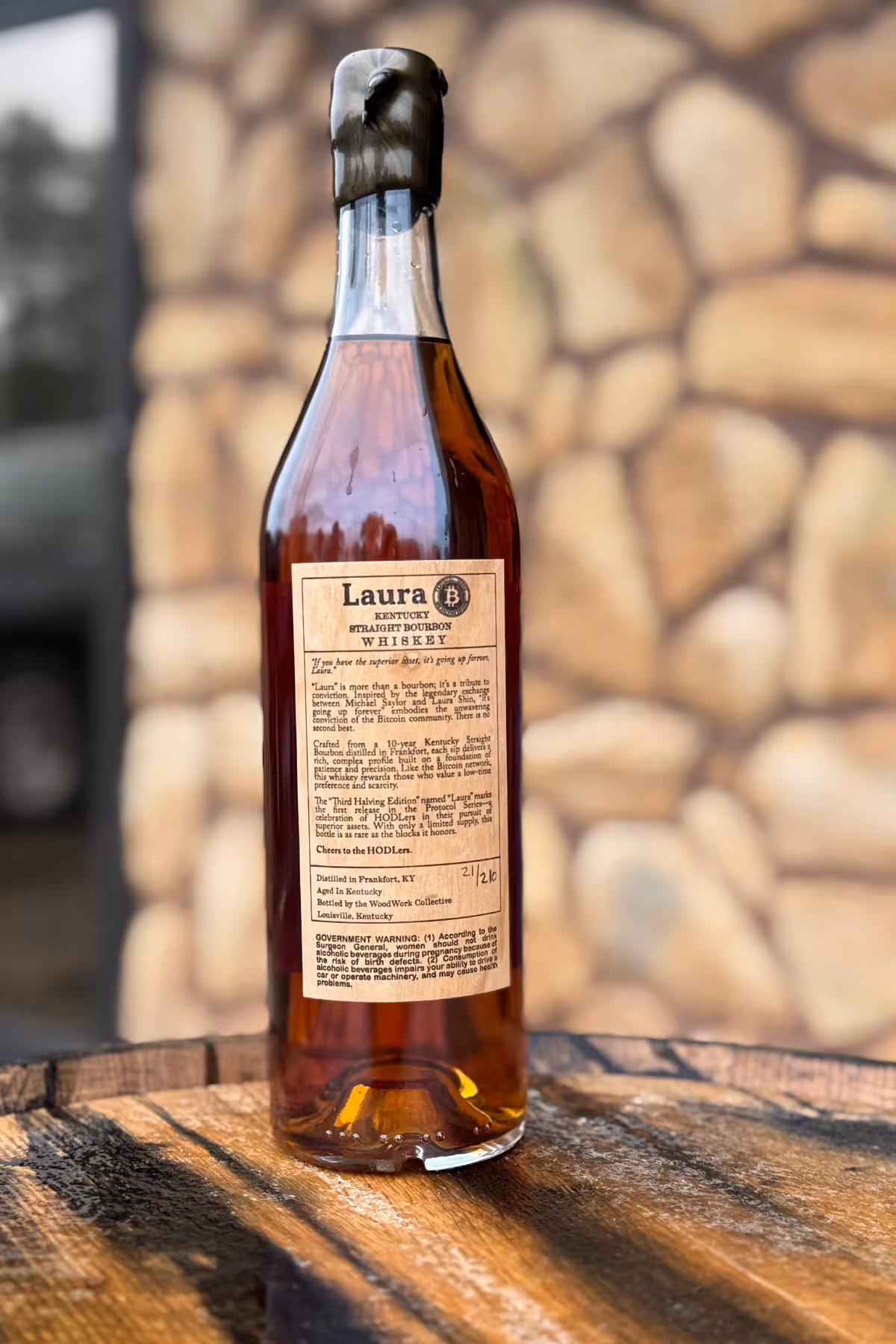 Laura Bitcoin Bourbon Bottle Near Outdoor Wall