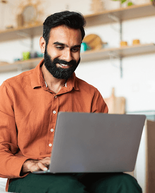 Two women interacting at a desk, one standing and smiling while the other is seated typing on a keyboard wearing a headset.