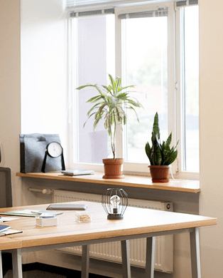 A woman with short blonde hair smiles and leans toward a seated woman with dark hair wearing a headset, who is typing on a keyboard.