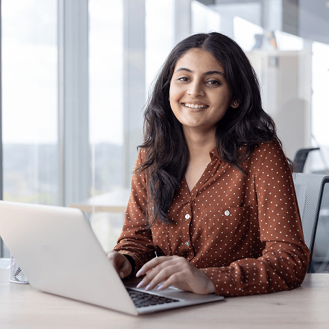 Five young adults smiling and cheering outdoors with trees in the background.