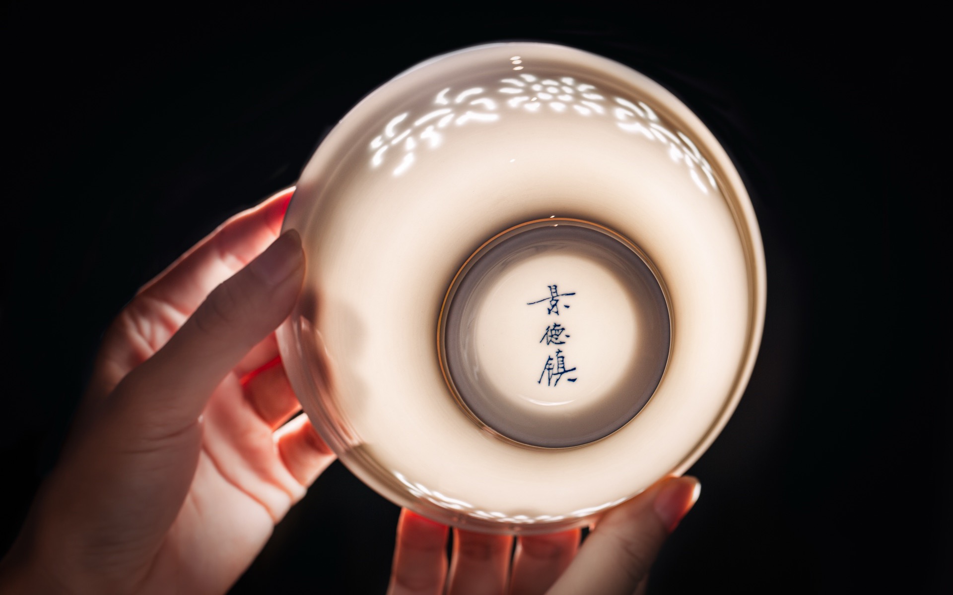 Imperiax porcelain bowl held to the light, showing its translucent pattern and Jingdezhen mark