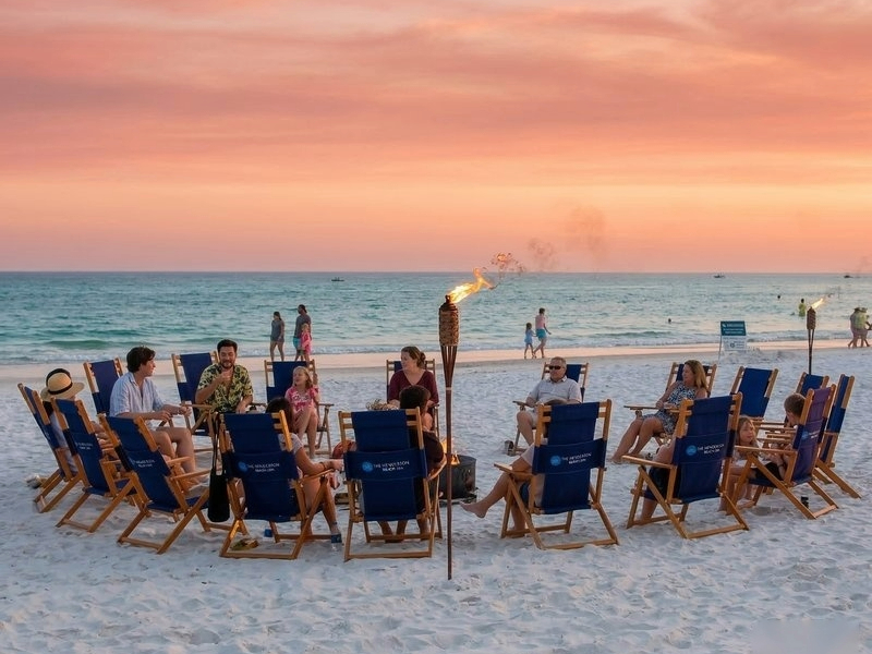 Family and friends gathered around a beach bonfire at sunset on 30A