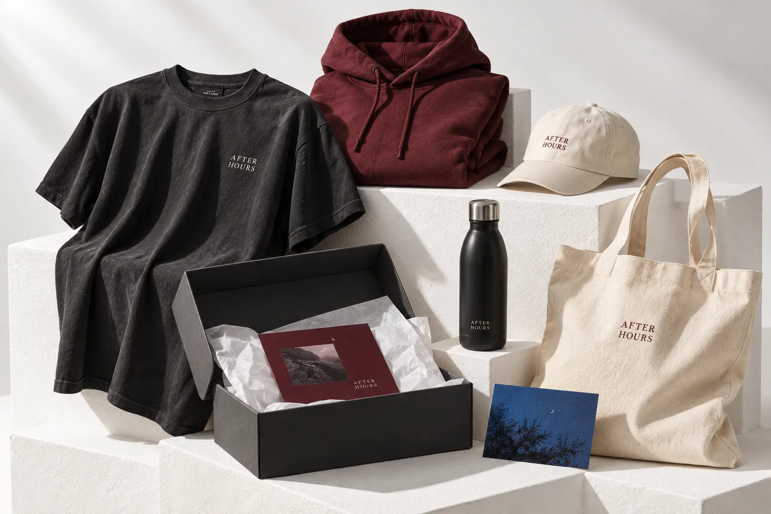 Creator merchandise concept with charcoal tee, burgundy hoodie, cream cap, tote and branded mailer
