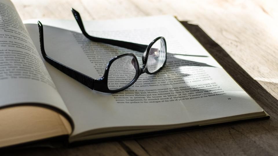 Paire de lunettes posée sur un livre - cession de magasin d'optique Montpellier - Cabinet Biot