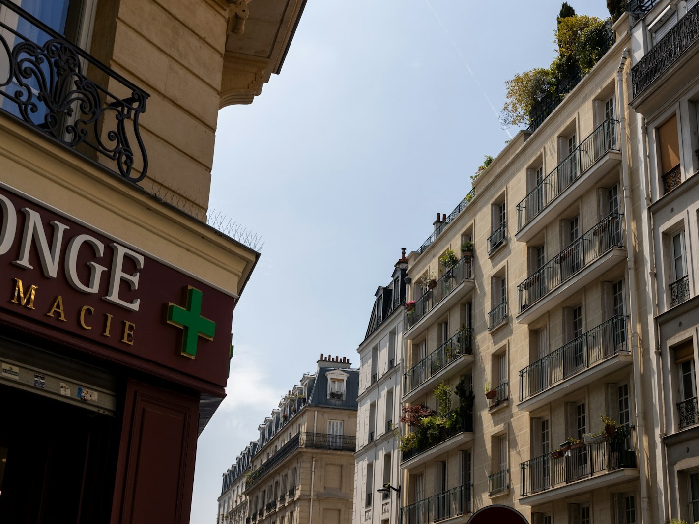 Enseigne et croix verte d'une pharmacie sur une façade de ville : racheter une officine, guide de l'acquéreur