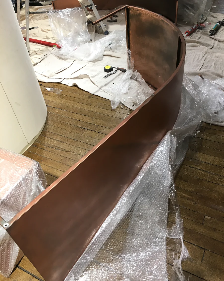 NU at Liberty · Curved metal-finish panel before fitting — installation photographs