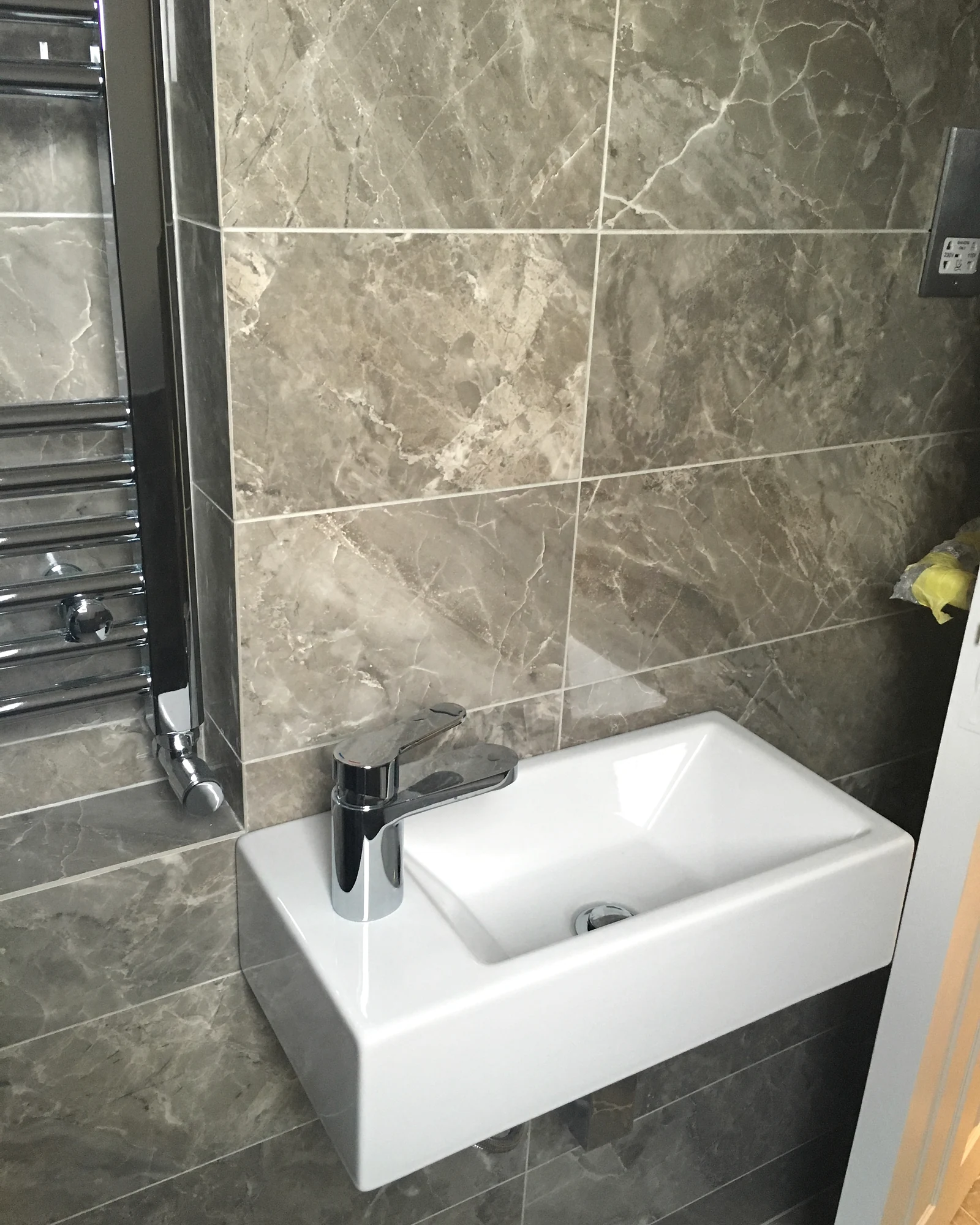 Basin and towel rail against veined bathroom surfaces