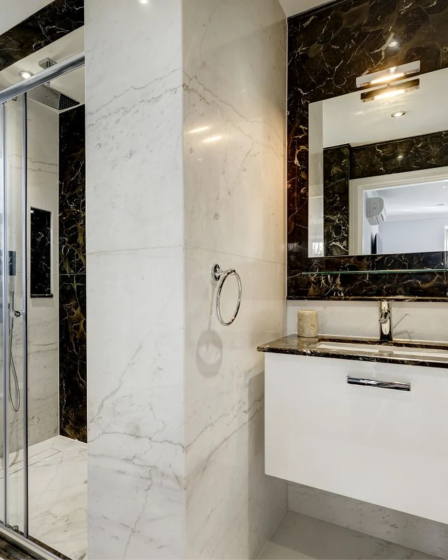 Contrasting stone borders around a bathroom mirror and shower