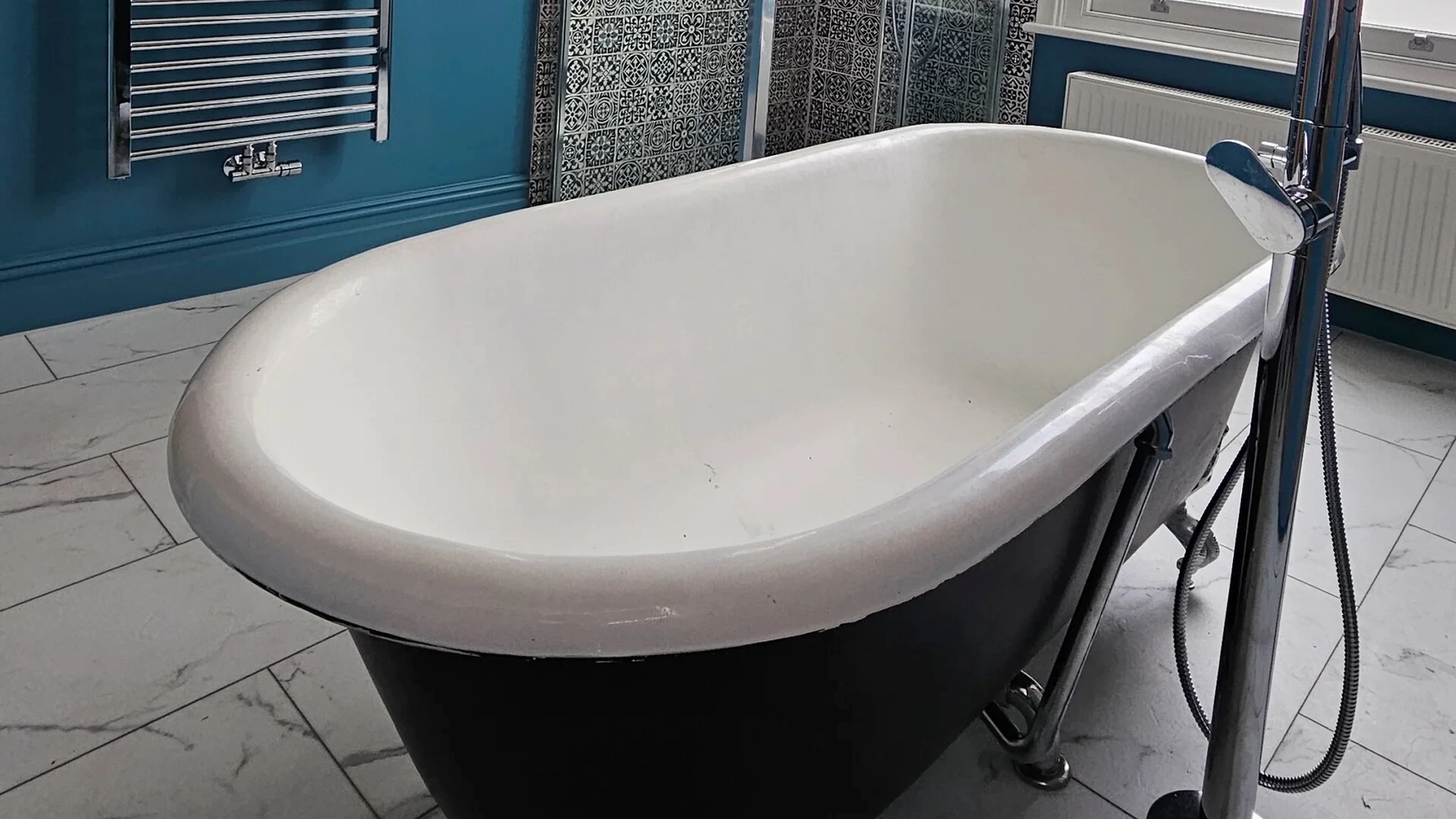 Freestanding bath beside a sash window in the Highbury house