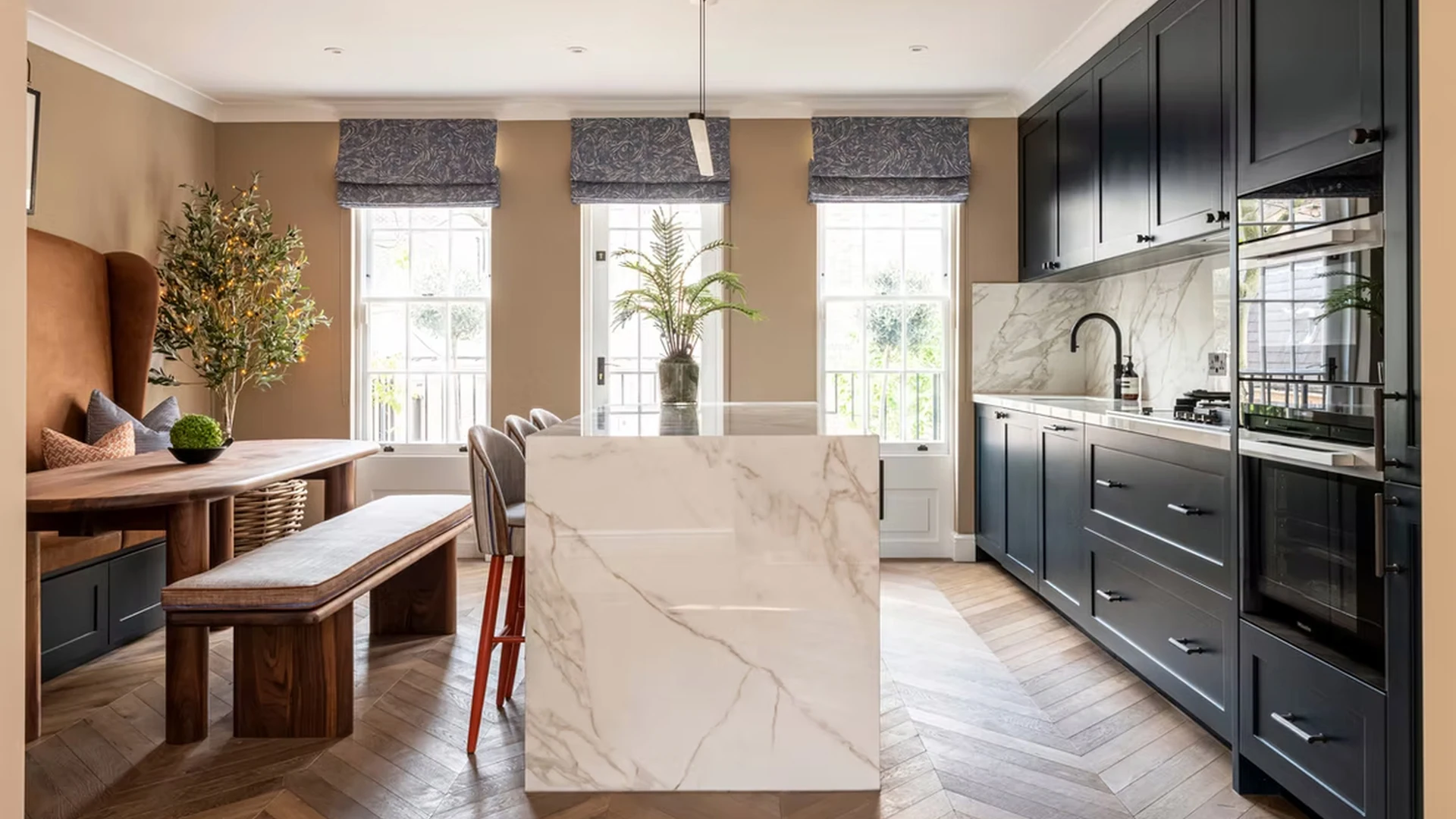 Bourne Street kitchen with a veined porcelain island, fitted banquette and dark cabinetry