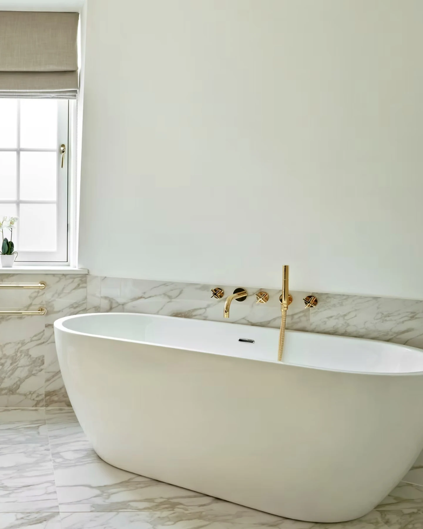Knightsbridge bathroom with a freestanding bath, veined surfaces and brass fittings